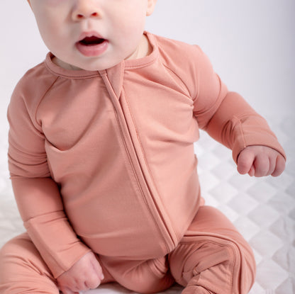 Baby wearing a pink onesie with a zipper on a light background
