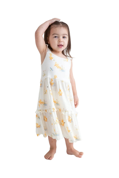 Young girl wearing a white dress with yellow floral patterns on a white background