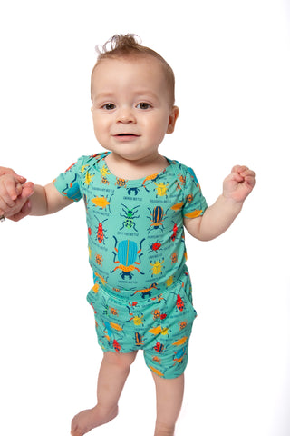 Baby wearing a colorful bug-themed outfit on a white background