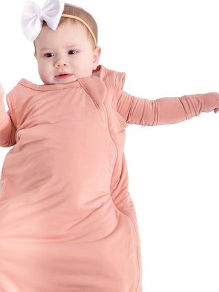 Baby in a pink swaddle with a white bow on a white background