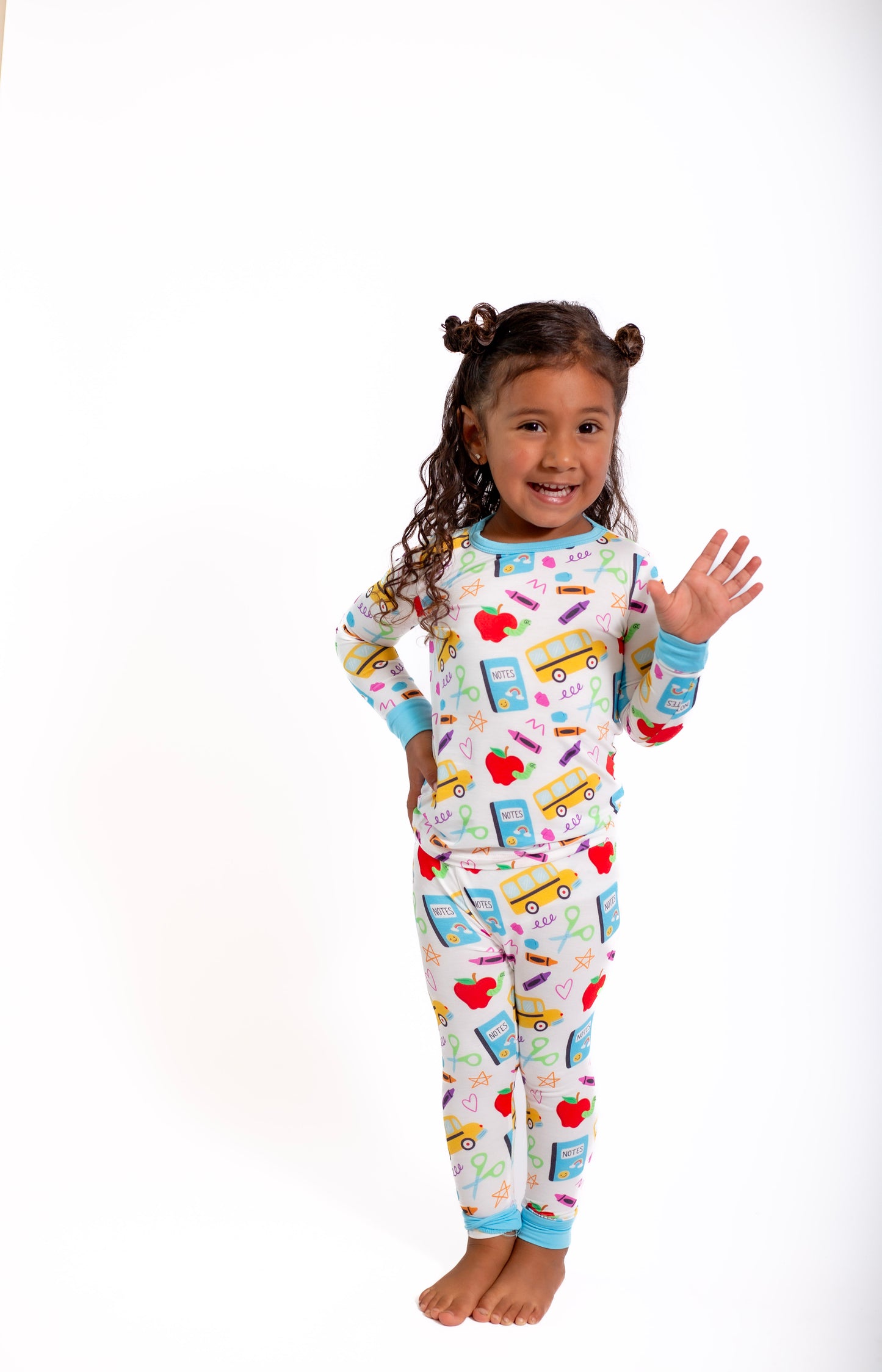 Child wearing colorful pajamas with school-themed design on a white background