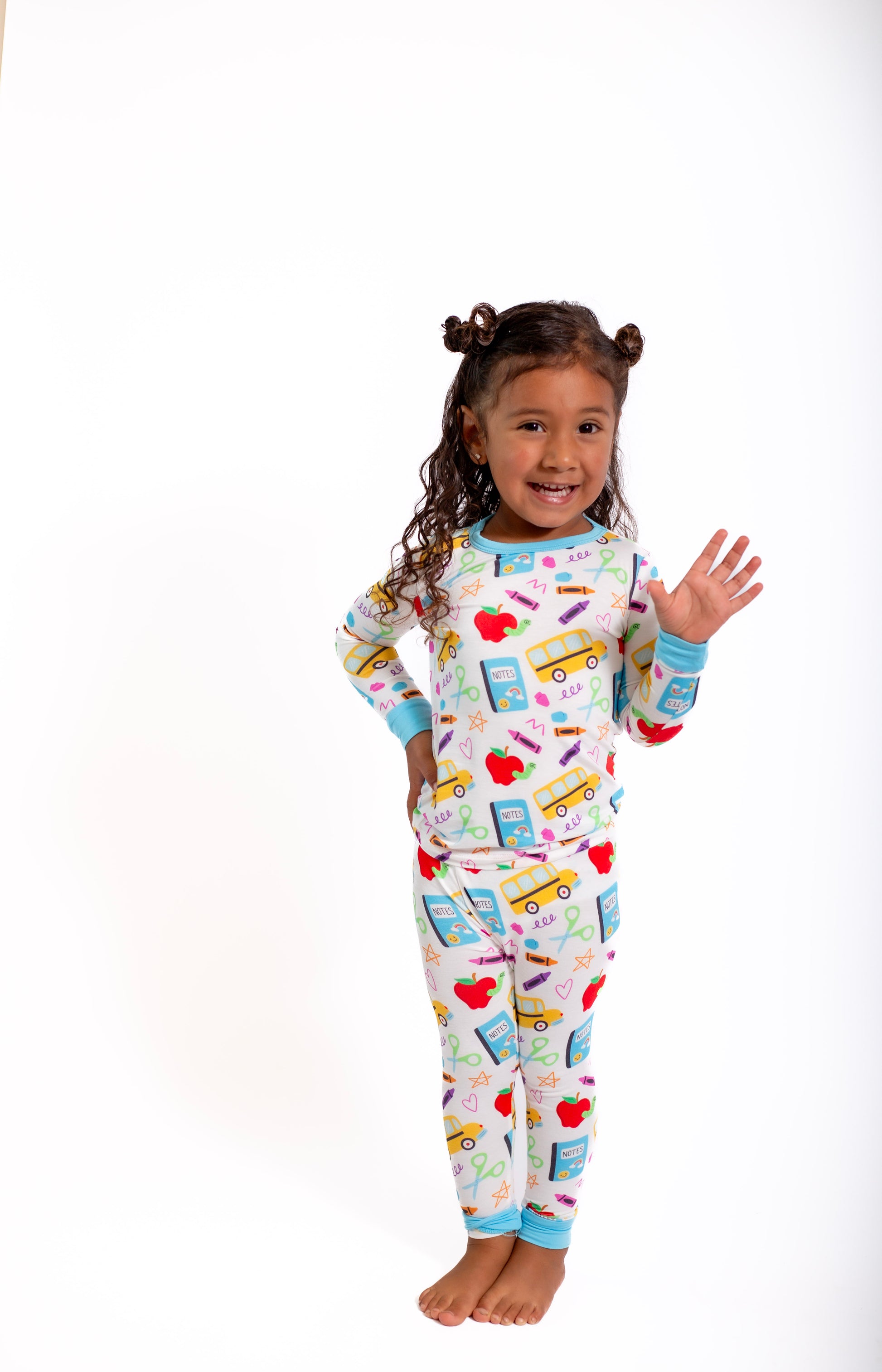 Child wearing colorful pajamas with school-themed design on a white background