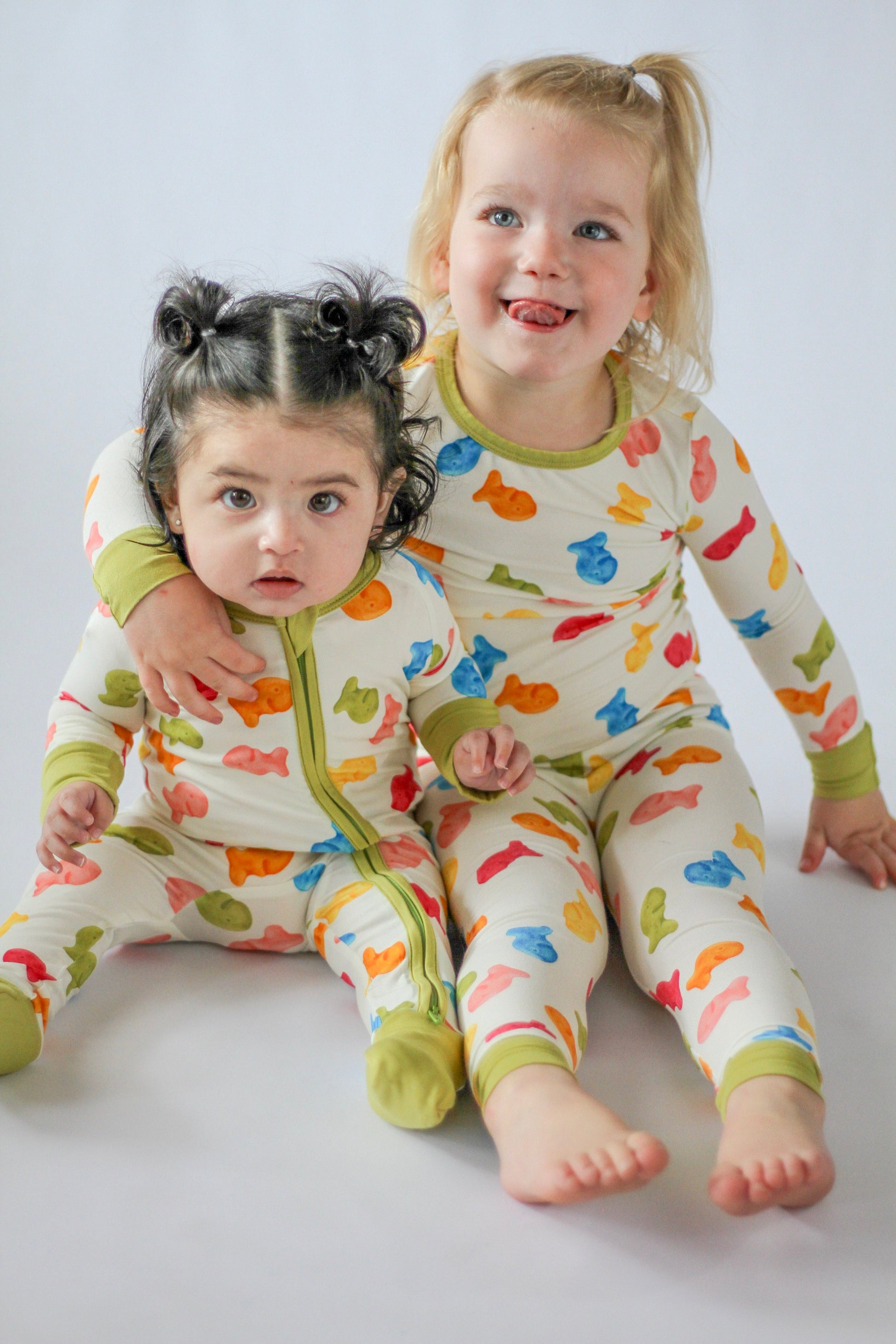 Two children wearing colorful pajamas with animal prints on a plain background