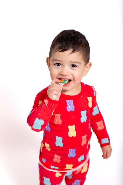 Child wearing a red pajama set with teddy bear patterns, holding a colorful object.
