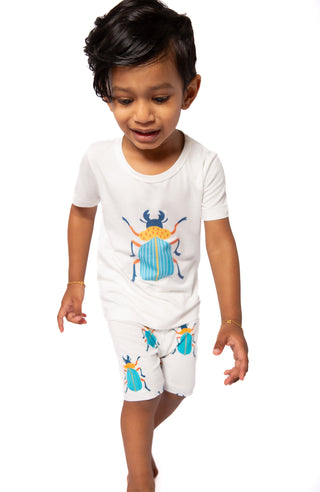 Child wearing a white outfit with beetle designs on a white background