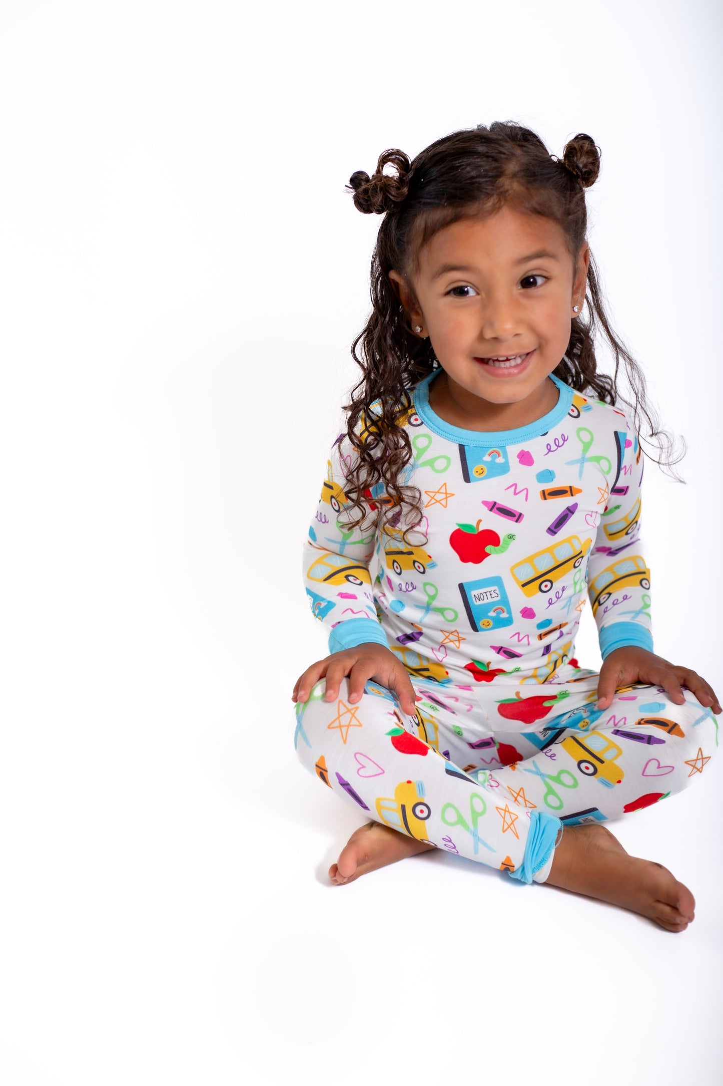 Child wearing colorful pajamas with school-themed design on a white background