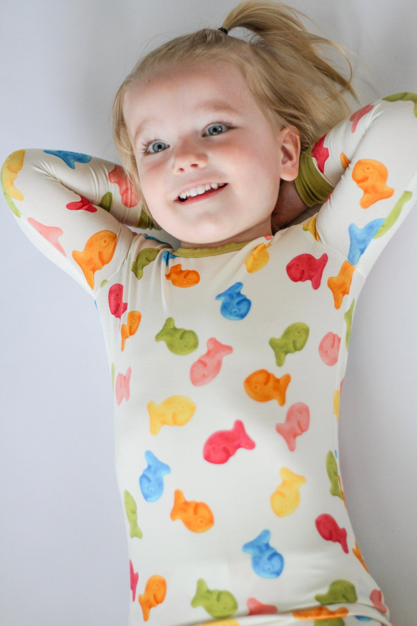 Child wearing a colorful fish-patterned onesie against a plain background