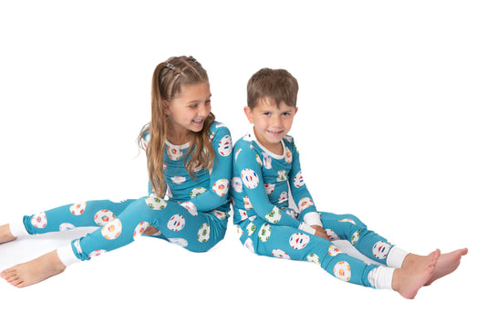 Two children wearing matching pajamas with a floral pattern on a white background