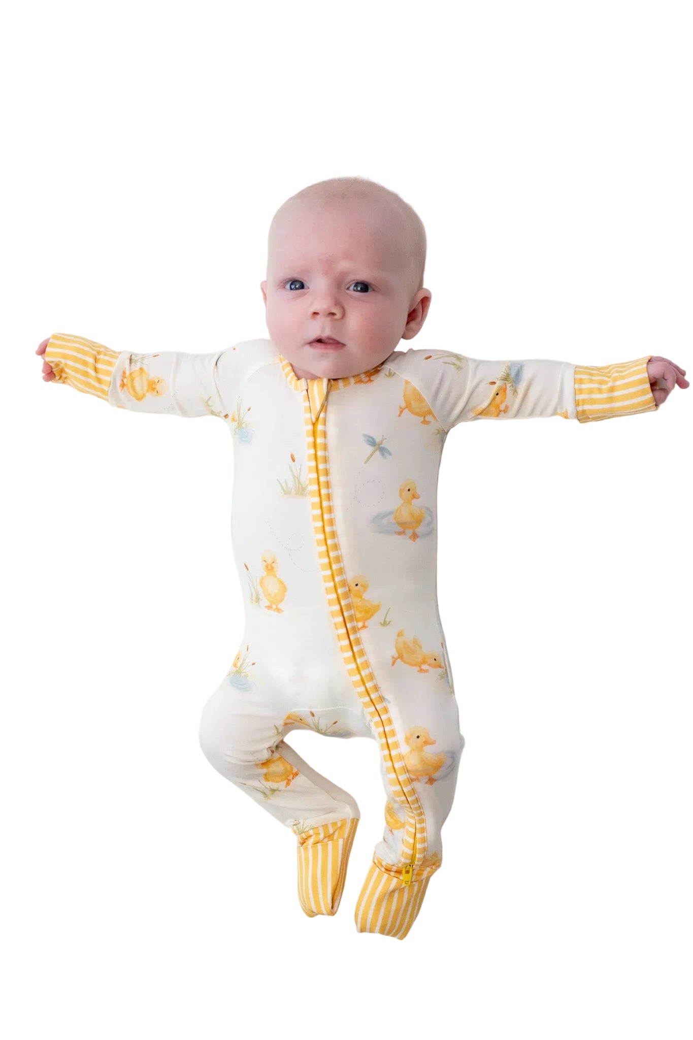 Baby wearing a white onesie with yellow duck patterns on a white background